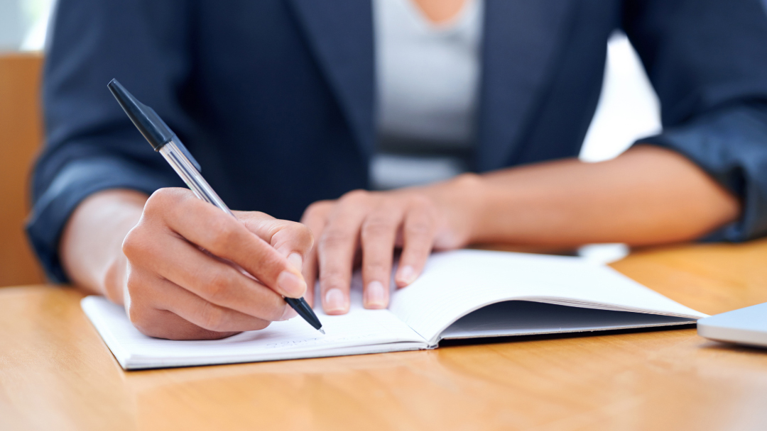 Un personne écrit dans un cahier